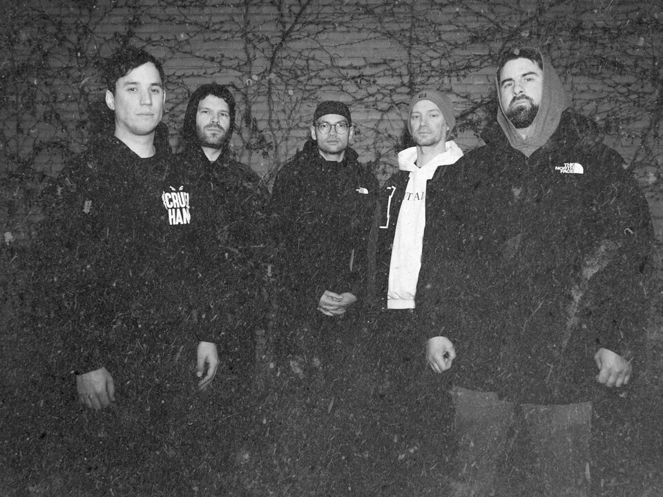 The five members of Exhale in front of a brick wall at night